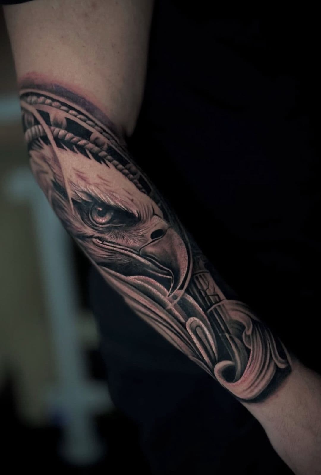 Aguia realista em preto e cinza com detalhes ornamentais no antebraco